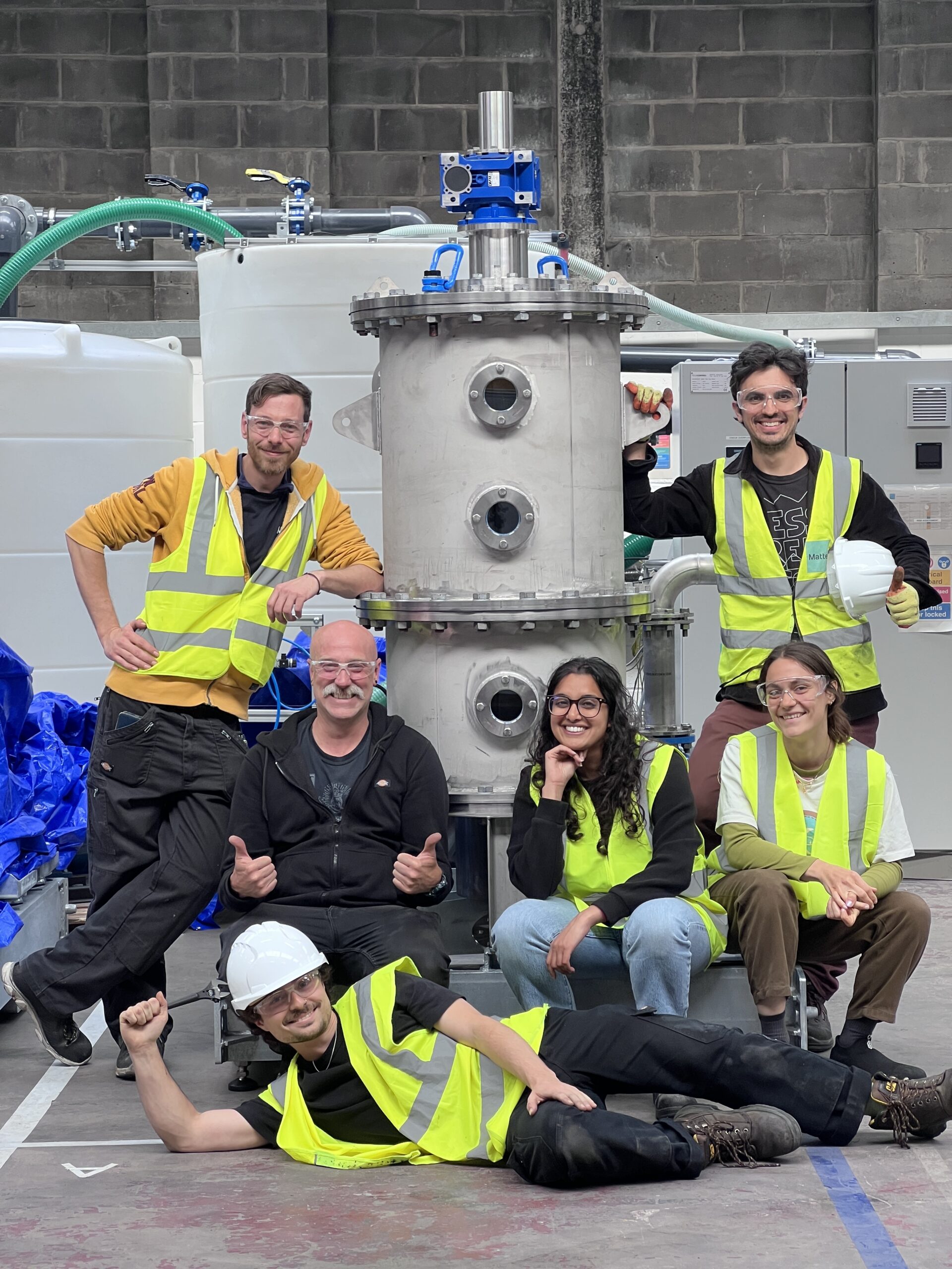 A group of people in safety equipment next to equipment.